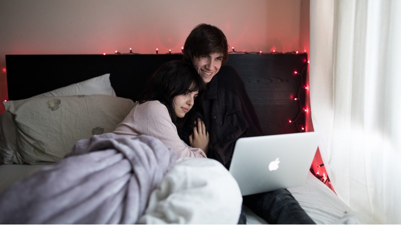 a couple watching a movie on a laptop in bed