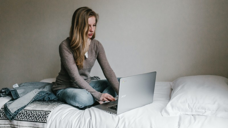 woman working on her laptop while sitting on a bed