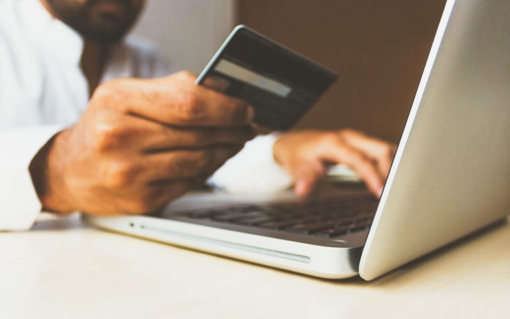 Man using a credit card to buy something via his laptop that is secured by the best VPN for Travel