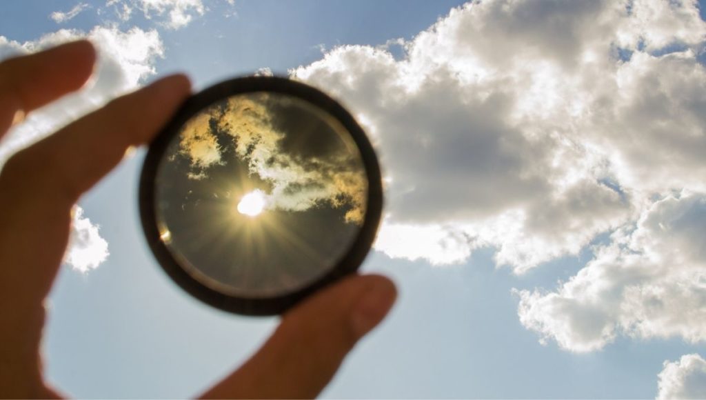 Someone holding up a polarizing lens filter to the sun
