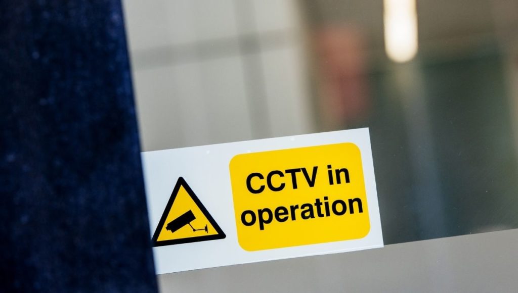 A small CCTV sticker in a window designed to deter the temptation of a breaking
