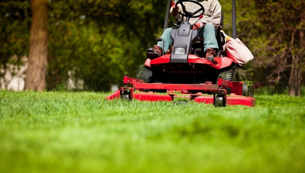 A person mowing the lawn with a ride on lawn mower