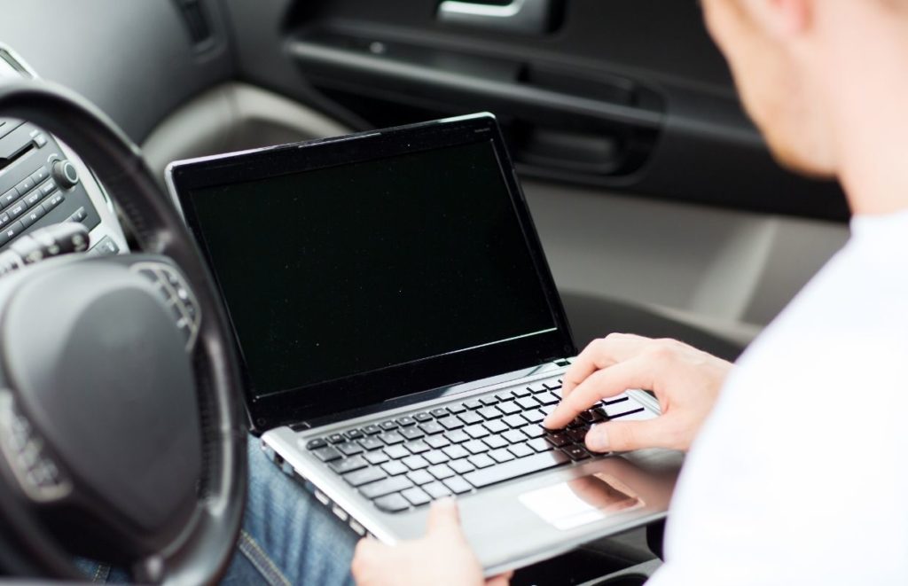 A man using a laptop in the car | Charging Laptops In Cars