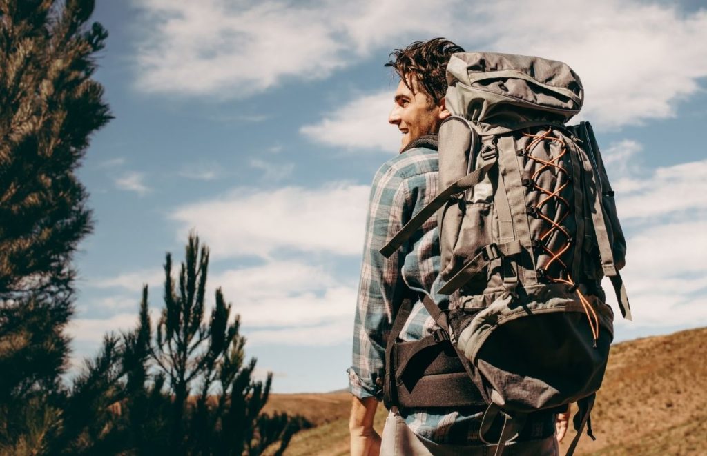 A man hiking while carrying the Best Cot for Backpacking