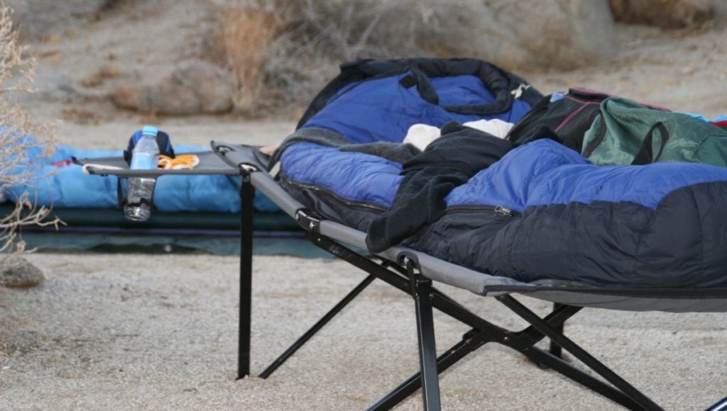 A camping bed on sand is not a great introduction to how to clean a camping cot