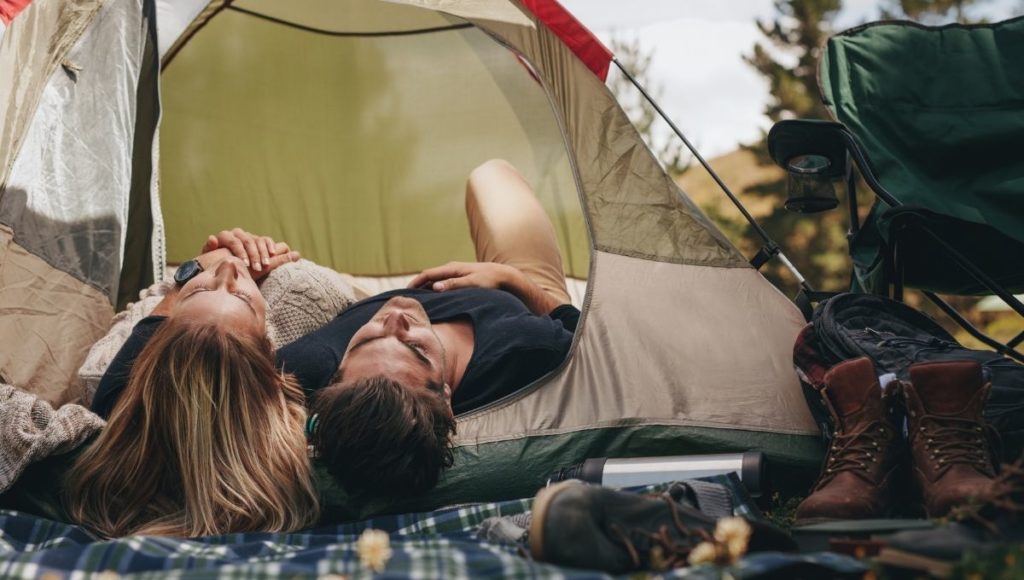 A couple looking up at the sky while lying down in a tent