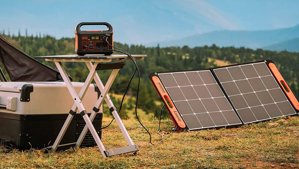 A solar generator battery is being charged outside the camp