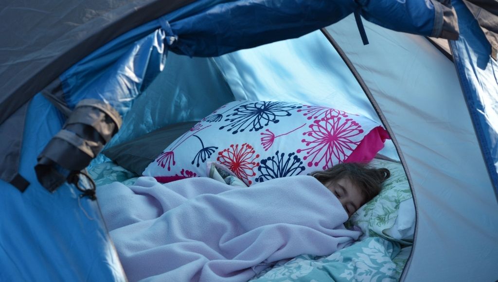 a baby girl sleeps in an air mattress camping bed