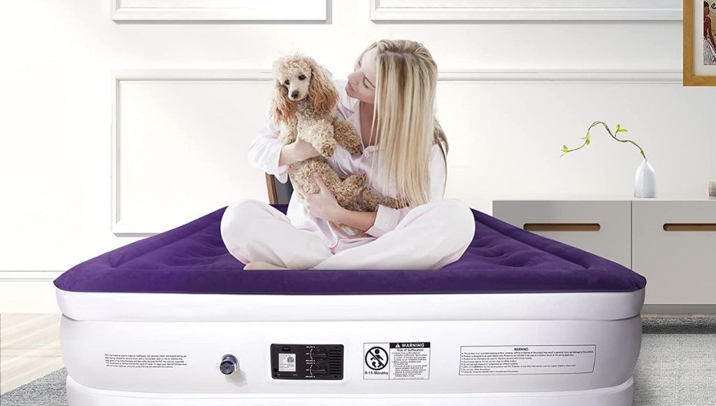 a girl sits on an air mattress bed with her dog