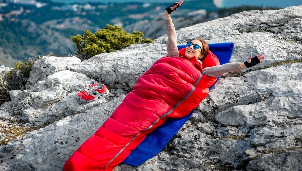 a lady sleep in a sleeping bag on the side of the hill