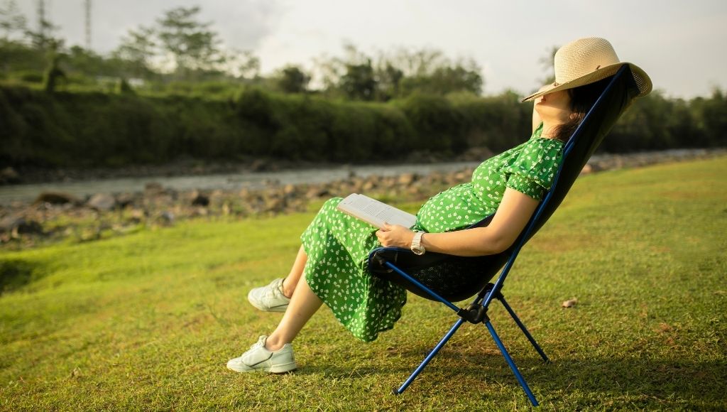 asian woman napping on camping helinox sunset chair in nature