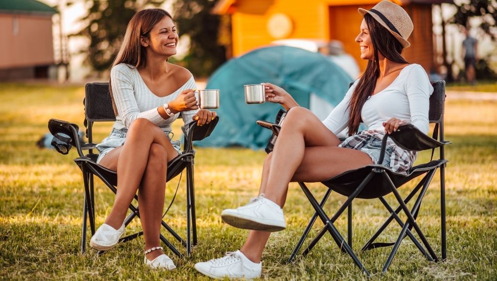 twomen sit in camping awn lounge chairs enjoying