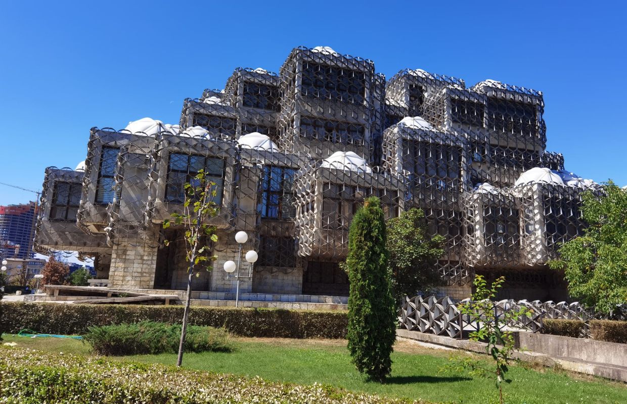 Looking up at The National Library of Kosovo with blue skies.