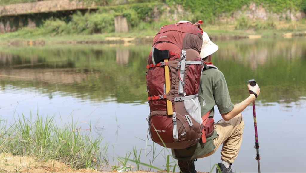 A man is looking at the river with its mountaintop 70L backpack on his shoulder