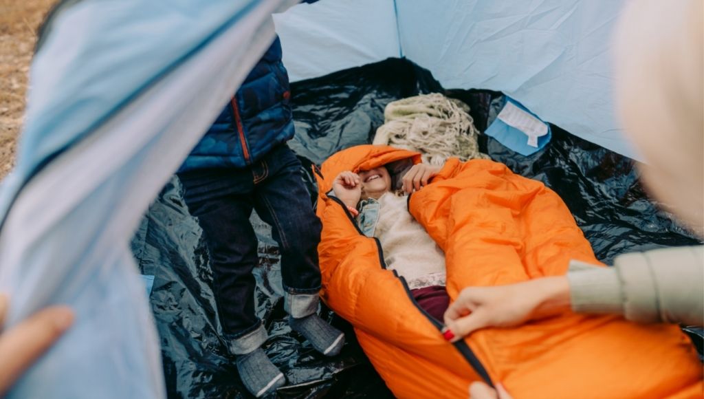 a girl is lying inside a sleeping bag