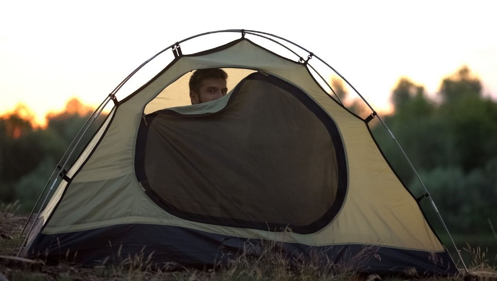 a boy into a zip closed camping tent