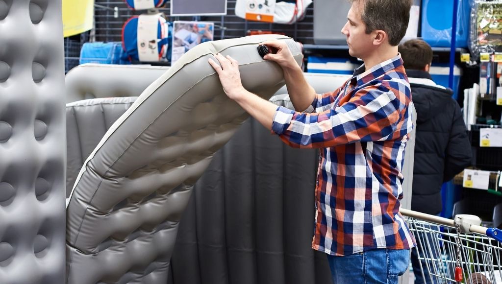 A man looking at the main points of an air mattress before buying