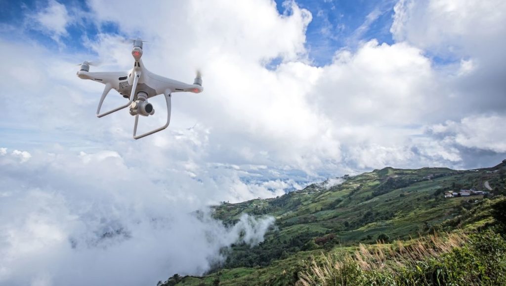 A white drone flying in the national park top hill