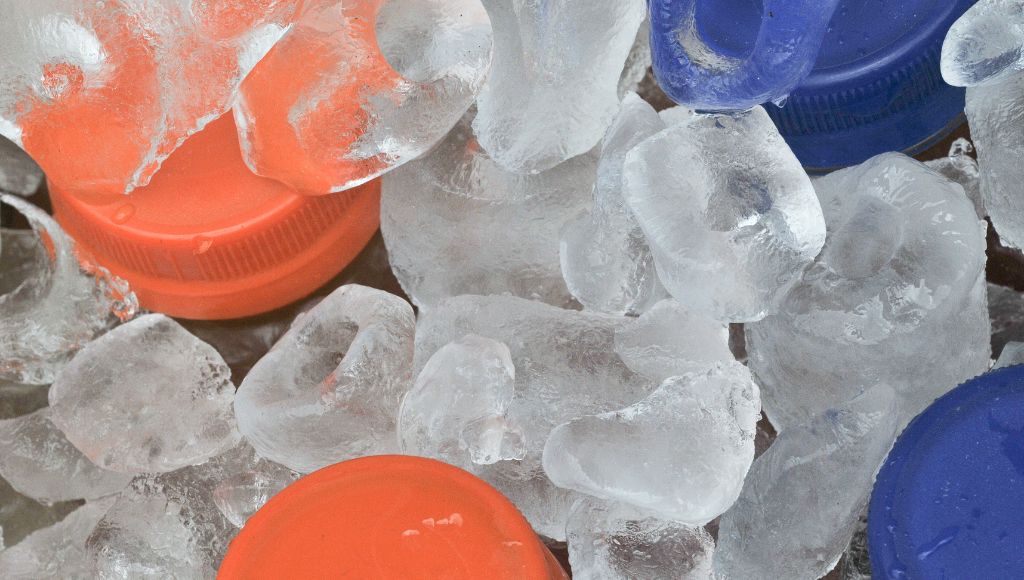 Bottles with orange and blue lids surrounded by ice