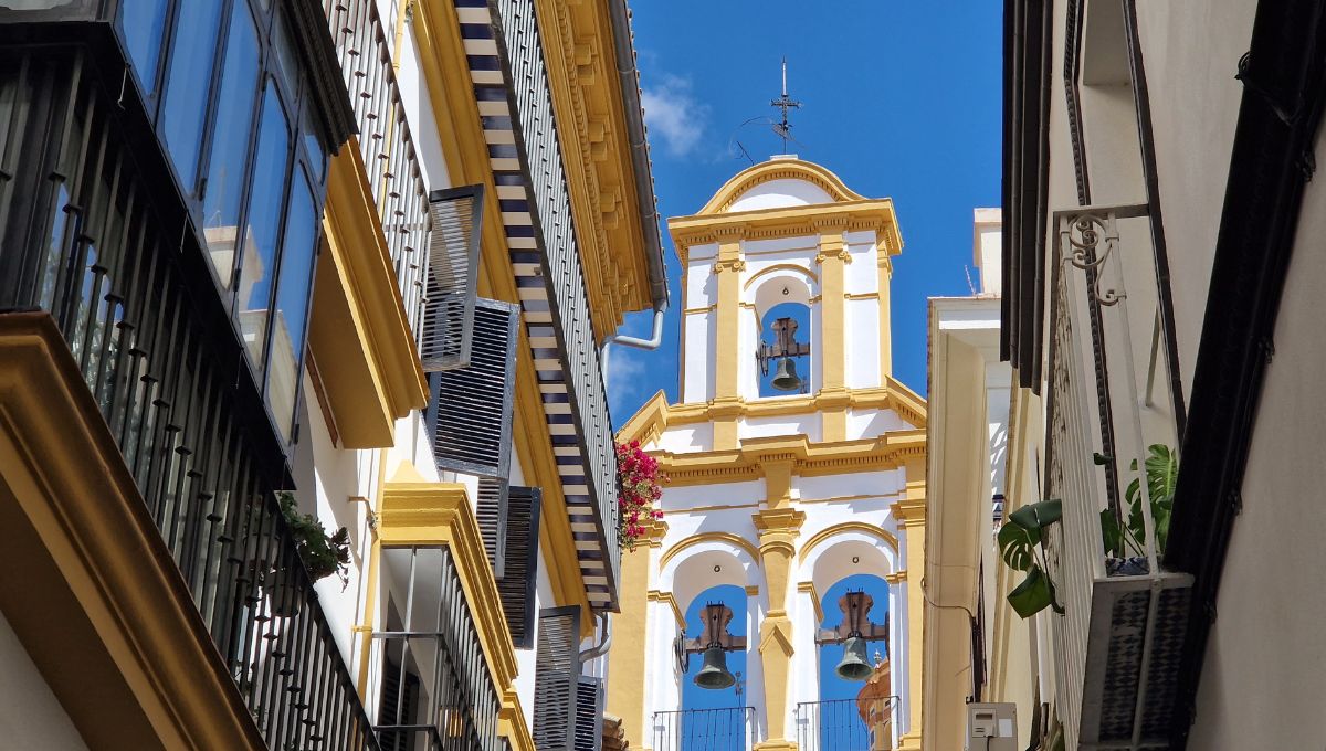 Chuch bells against a blue sky looking up from the narrow streets of Seville