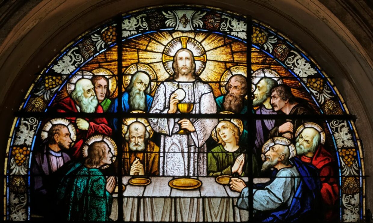 A stained glass window depicting the Last Supper with Jesus holding a cup that is now knows as the Holy Grail.