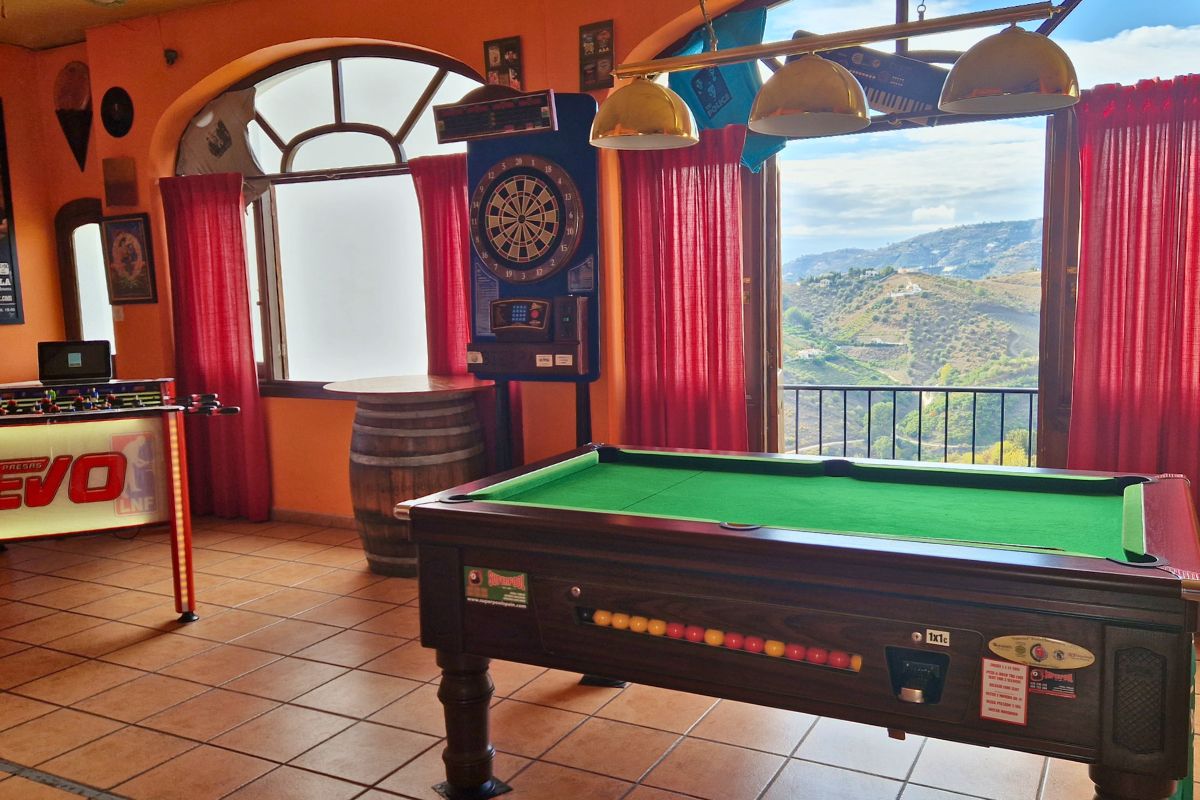 A Fussbale table, dartboard and pool table inside one of the bars in Andalusian white village Frigiliana with a view out to the mountainside