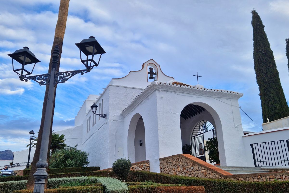 The white washed Ermita de San Sebastian set agains a blue sky with whispy clouds in the lower part of Frigiliana