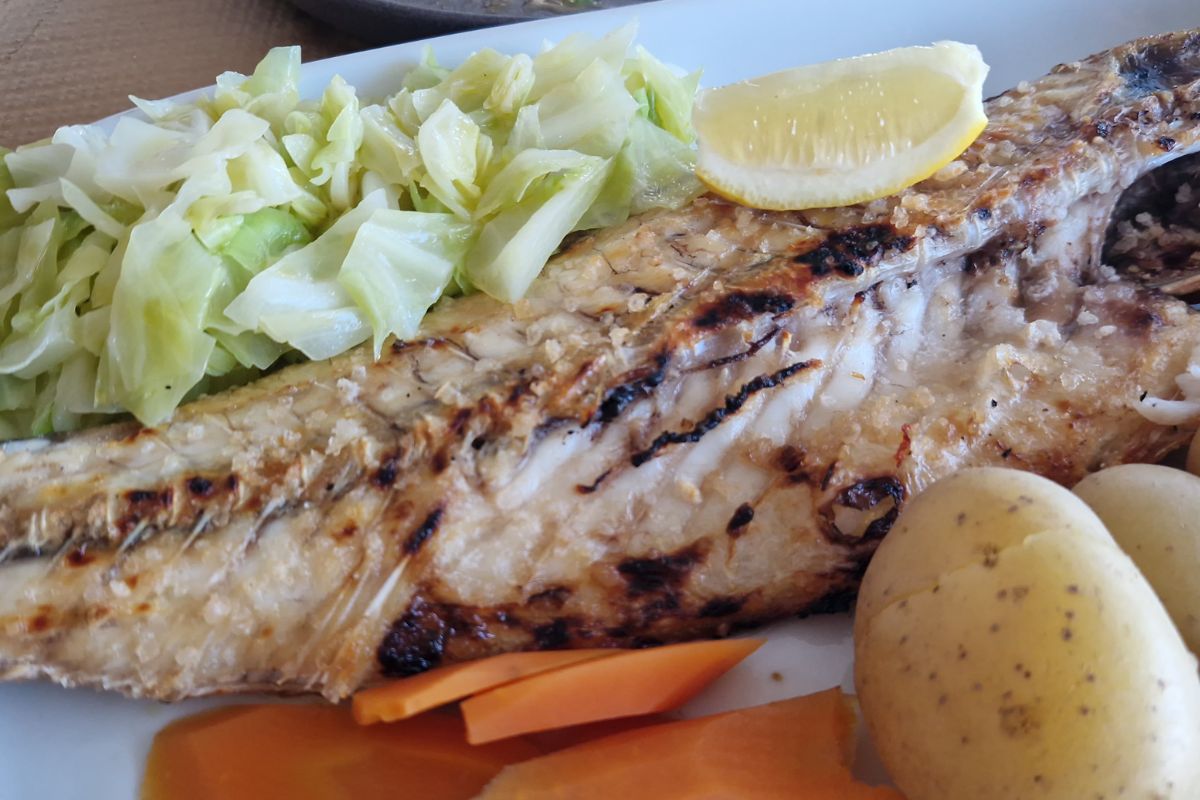 Freshly caught sea bass cooked over an open coal grill, served simply with fresh vegetables and potato at Restaurante A Rocha.